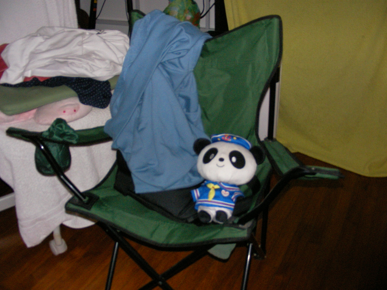 Stuffed Panda sitting in a camping-style folding chair. Image is noisy and out-of-focus with camera flash.